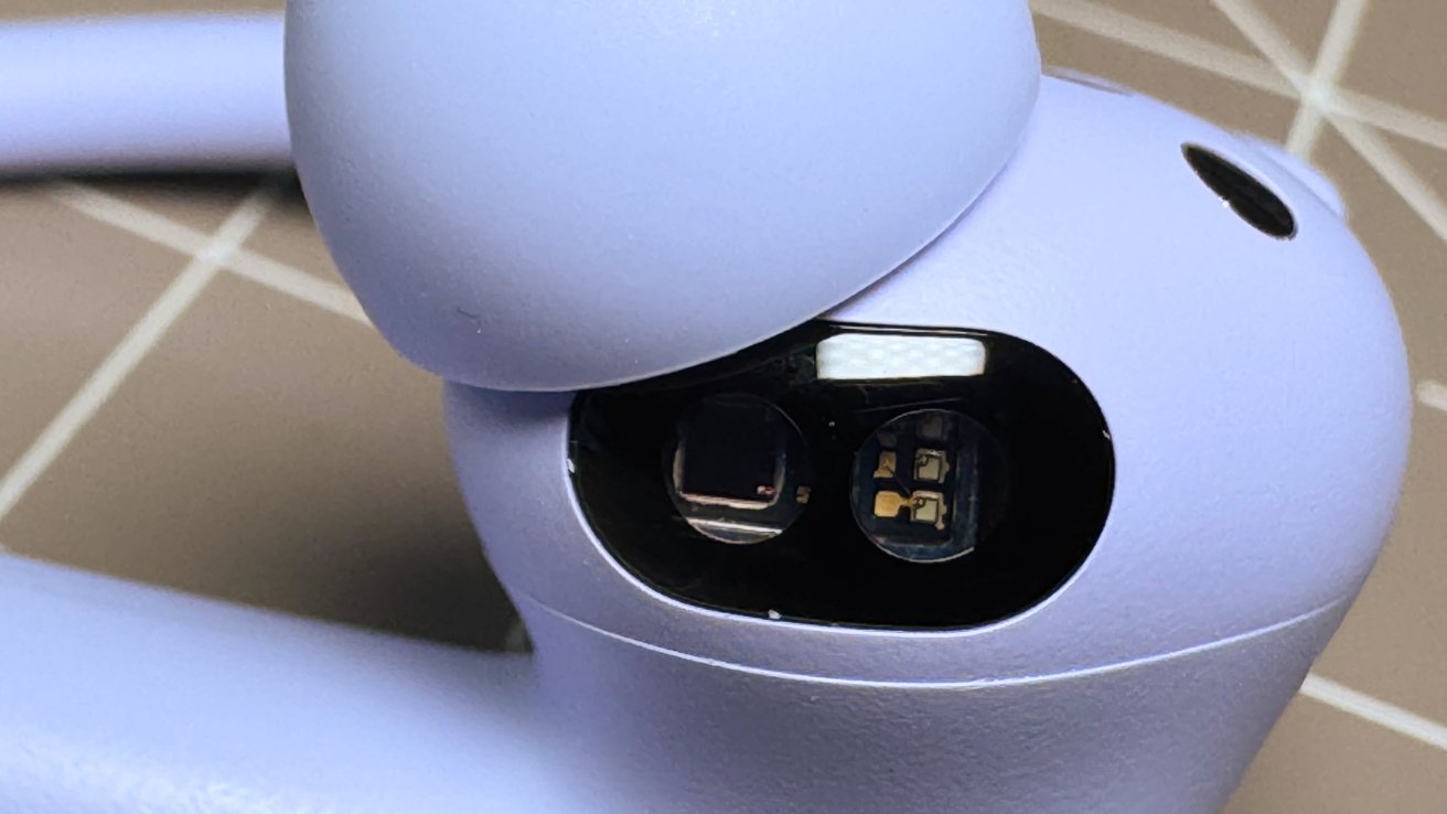 Close-up of a purple electronic device with visible sensors and components under a black oval cover.