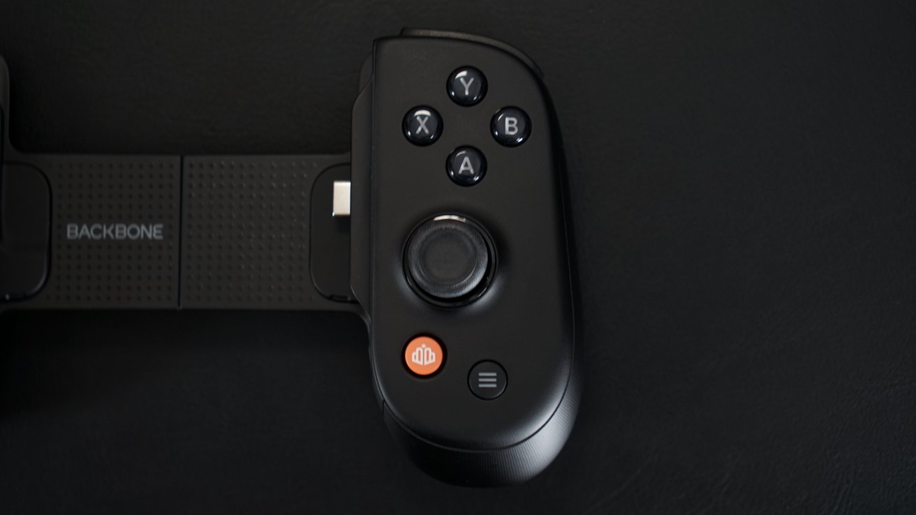 Black gaming controller with buttons labeled X, Y, A, B, joystick, and two additional orange and black buttons.